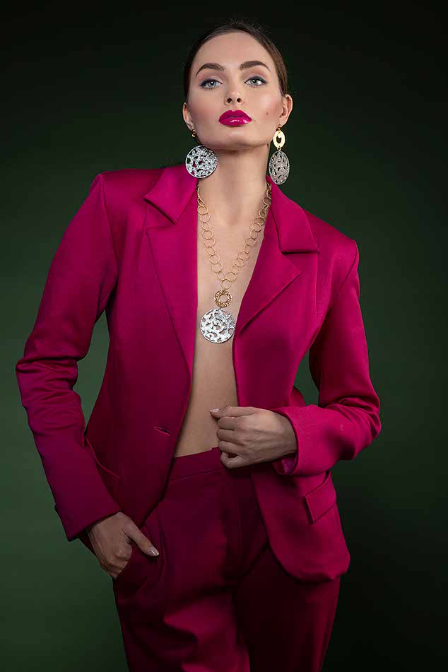 super model very beautiful looking in camera very sensual , wearing an elegant outfit , fucshia , with nice jewelry , posing on dark green background.