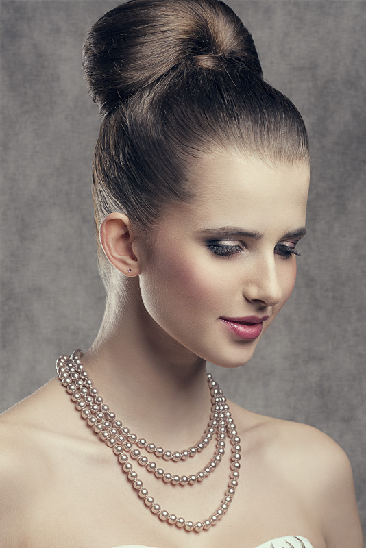 close-up portrait of fine brunette woman with elegant hair-style, stylish make-up and precious pearl necklace