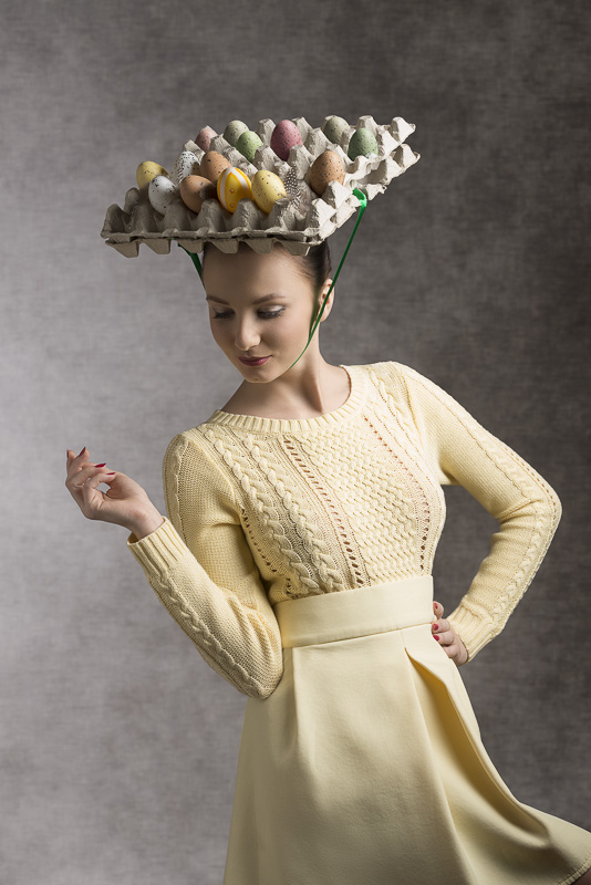 lovely easter portrait of beautiful brunette woman with yellow clothes and funny eggs box on the head